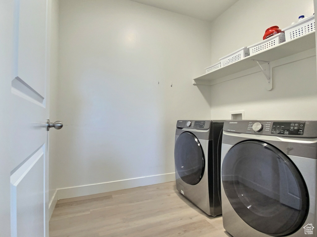 Clothes washing area featuring washing machine and dryer and light hardwood / wood-style floors