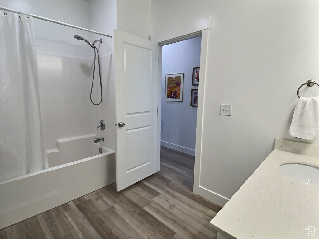 Bathroom with vanity, hardwood / wood-style flooring, and shower / bathtub combination with curtain
