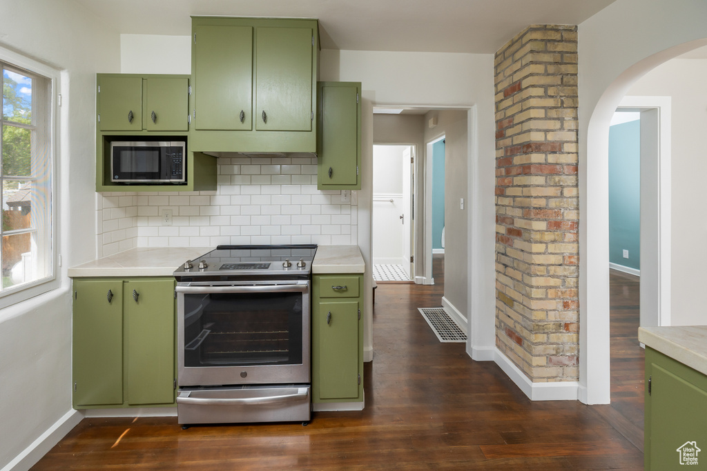 Kitchen featuring dark hardwood / wood-style flooring, appliances with stainless steel finishes, backsplash, and green cabinets