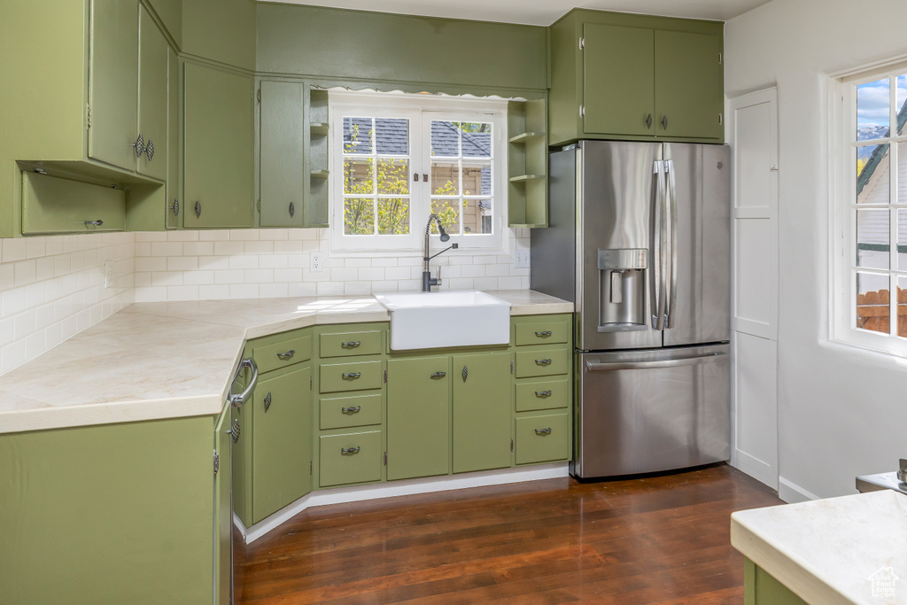 Kitchen with sink, dark hardwood / wood-style flooring, green cabinets, and stainless steel fridge with ice dispenser