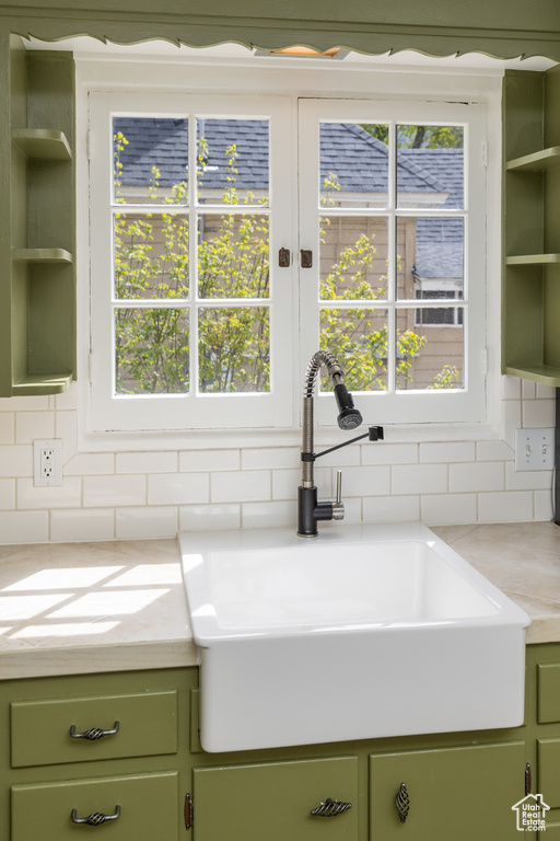 Kitchen with a wealth of natural light, green cabinetry, and sink