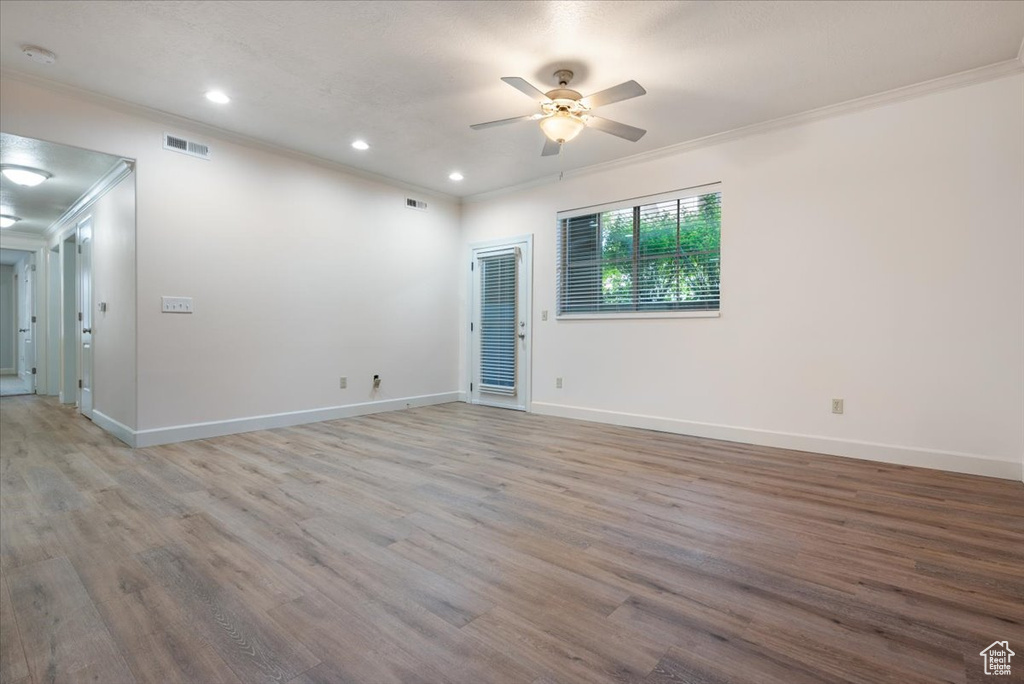 Empty room featuring ceiling fan, hardwood / wood-style flooring, and ornamental molding