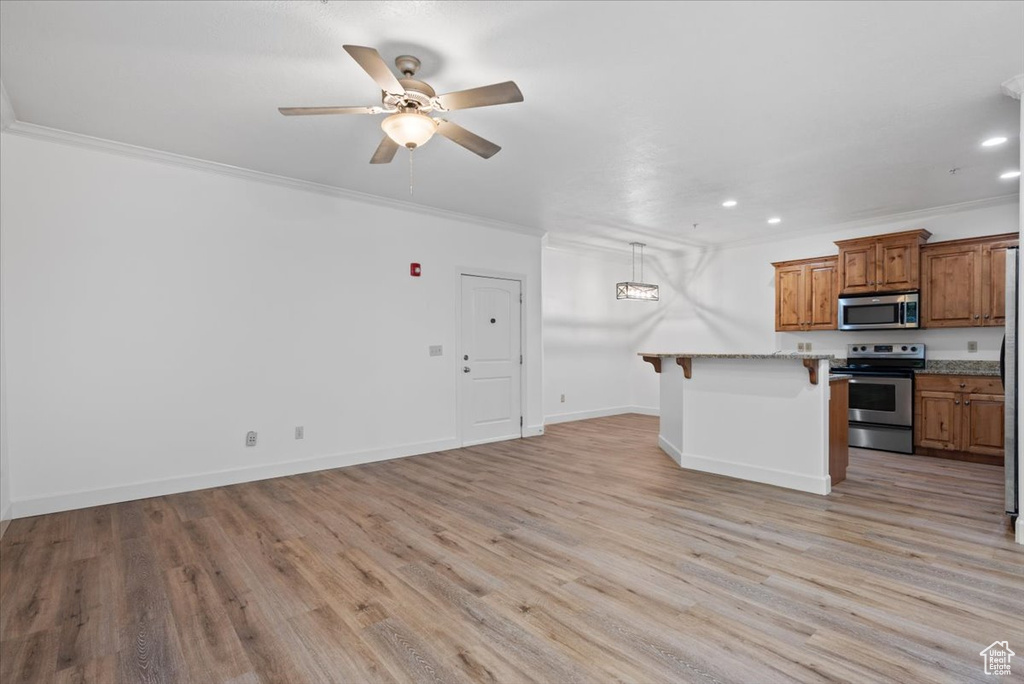 Kitchen with appliances with stainless steel finishes, ceiling fan, light hardwood / wood-style floors, and a breakfast bar