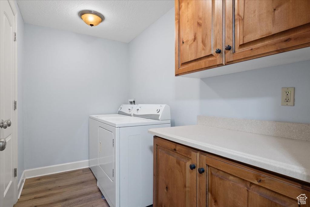Laundry room featuring cabinets, hardwood / wood-style floors, and washer and dryer