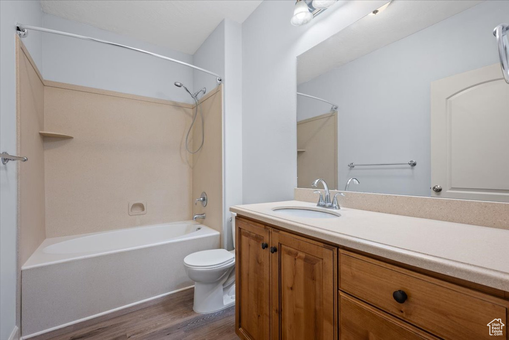 Full bathroom featuring toilet, oversized vanity, hardwood / wood-style floors, and shower / bathtub combination