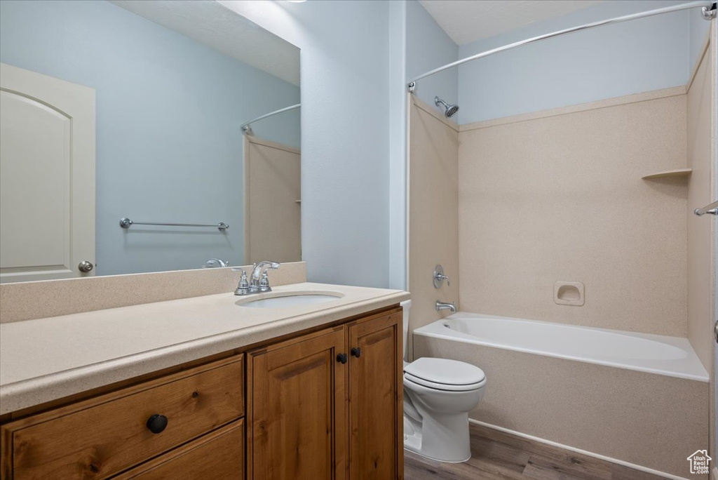 Full bathroom featuring hardwood / wood-style floors, shower / bathing tub combination, vanity, and toilet