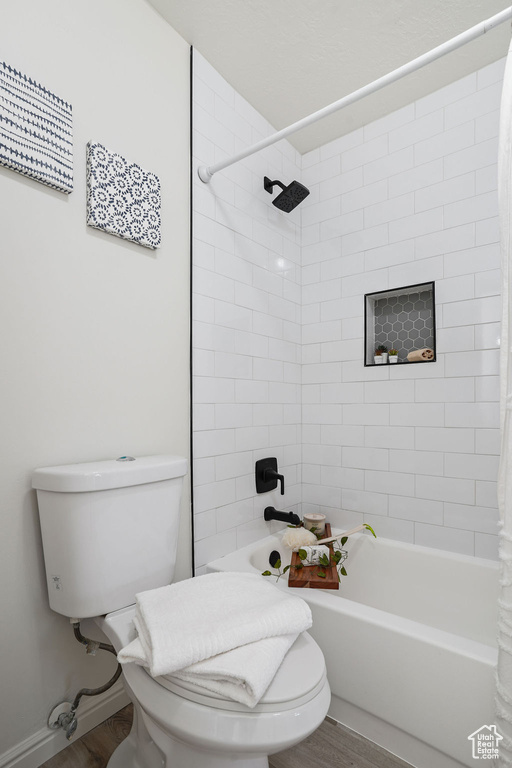 Bathroom featuring hardwood / wood-style floors, shower / bath combo, and toilet