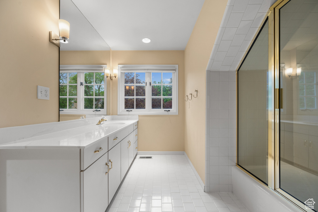 Bathroom with plenty of natural light, tile floors, combined bath / shower with glass door, and vanity