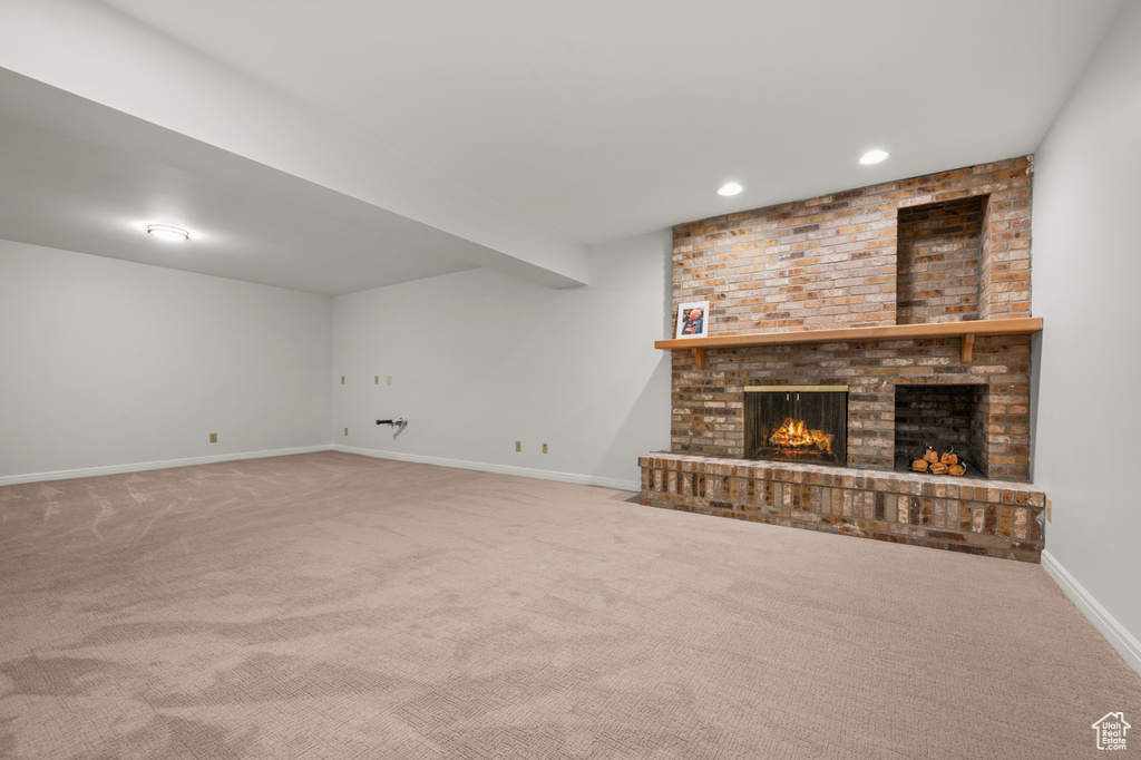 Unfurnished living room with brick wall, a brick fireplace, and carpet floors