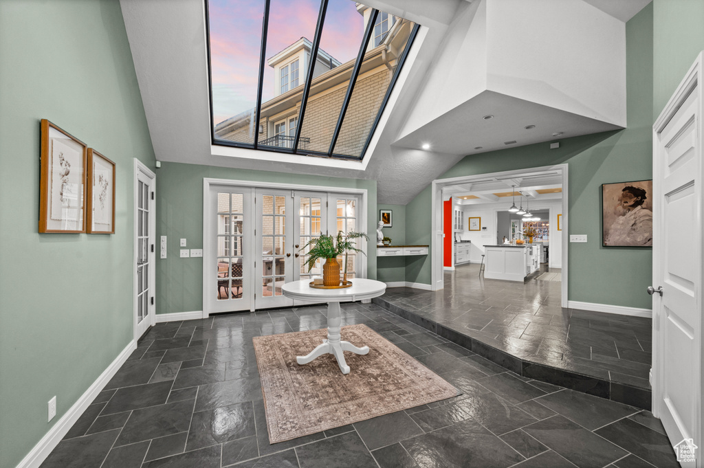 Foyer with a skylight, french doors, a high ceiling, and dark tile floors