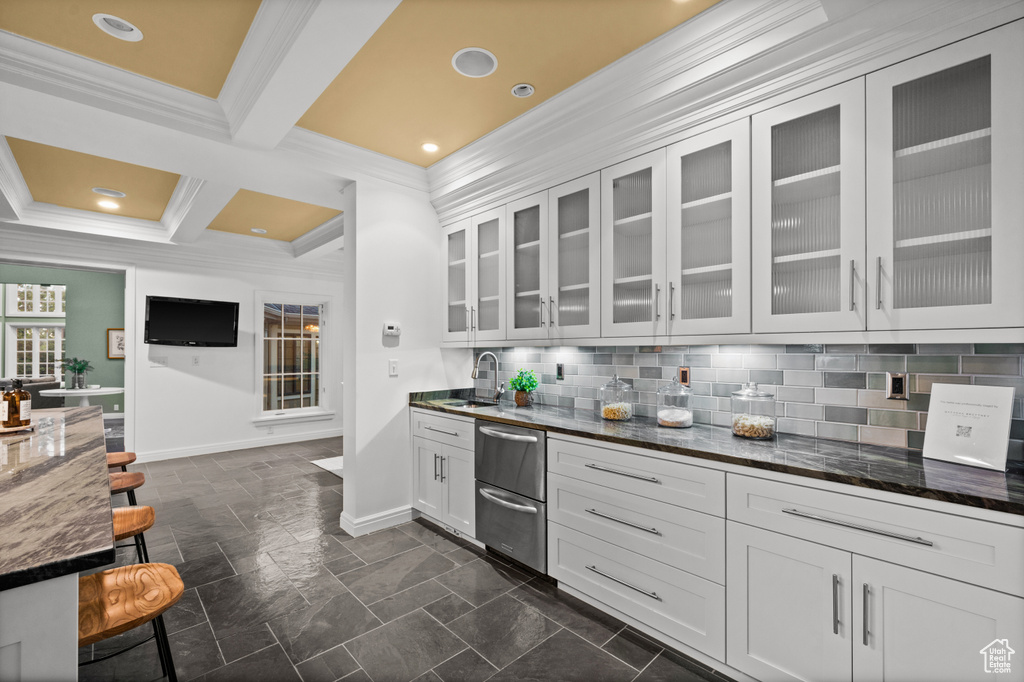 Kitchen featuring crown molding, white cabinetry, beam ceiling, tasteful backsplash, and dark stone countertops