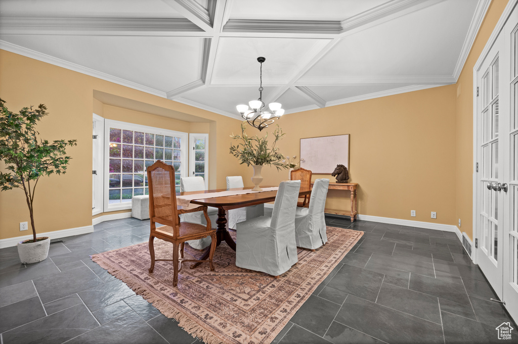 Tiled dining area with ornamental molding, a notable chandelier, and coffered ceiling