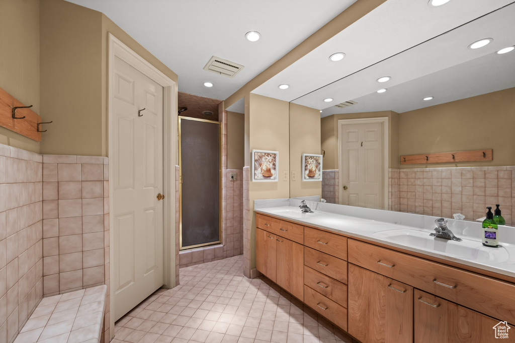 Bathroom with tile walls, large vanity, tile flooring, an enclosed shower, and dual sinks