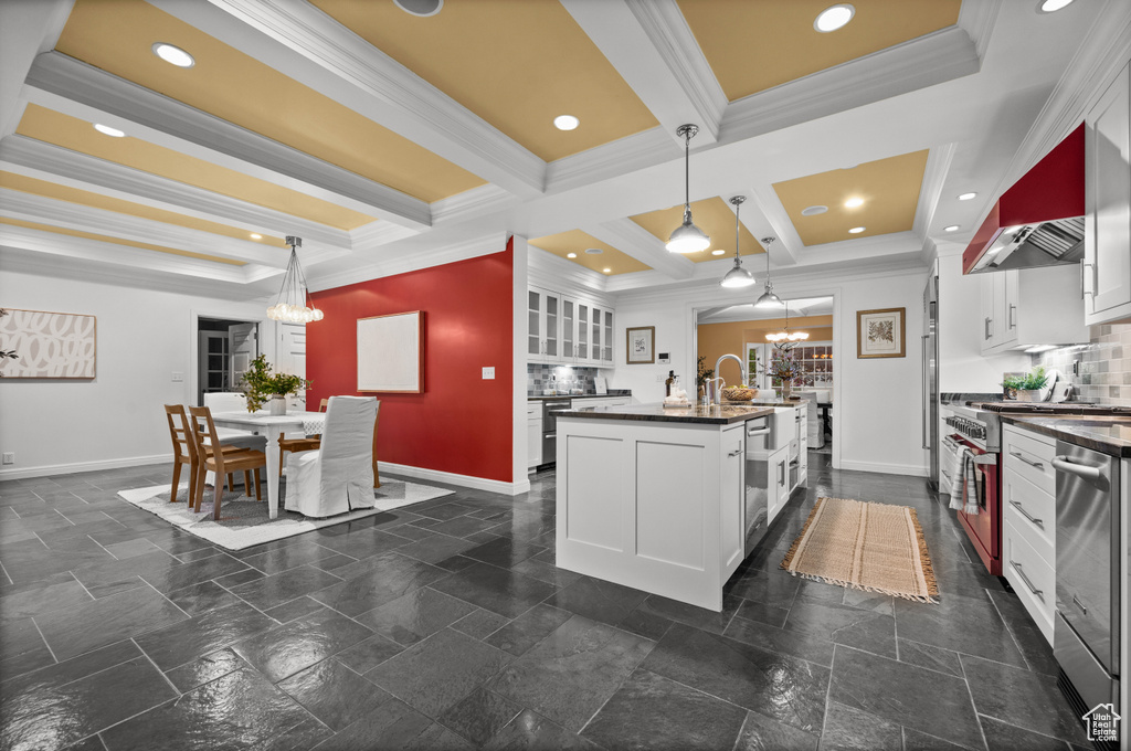 Kitchen featuring ventilation hood, decorative light fixtures, tasteful backsplash, dark tile flooring, and beamed ceiling