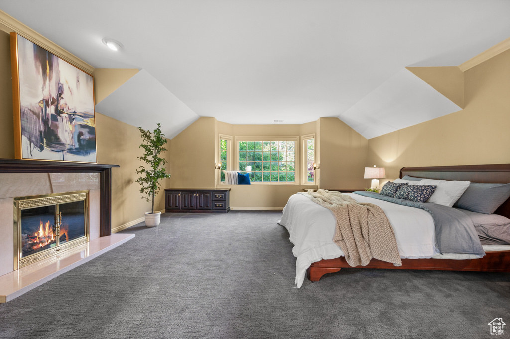 Carpeted bedroom featuring vaulted ceiling and a high end fireplace
