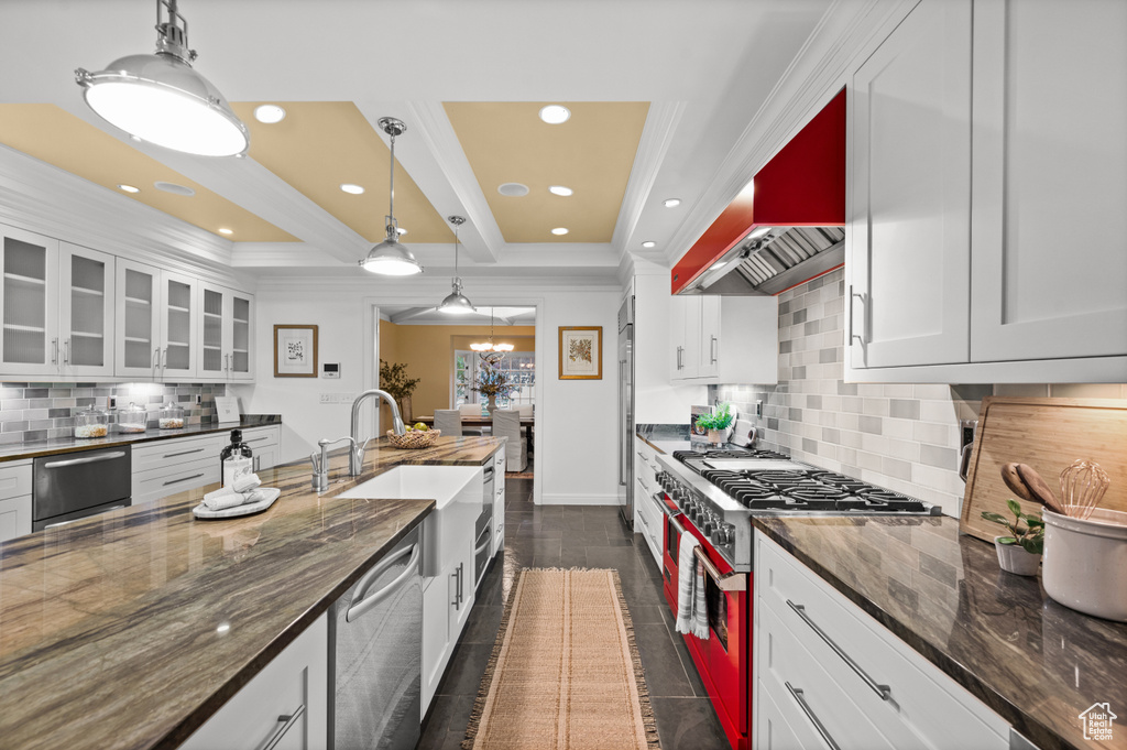Kitchen with dark tile floors, gas range oven, backsplash, decorative light fixtures, and stainless steel dishwasher