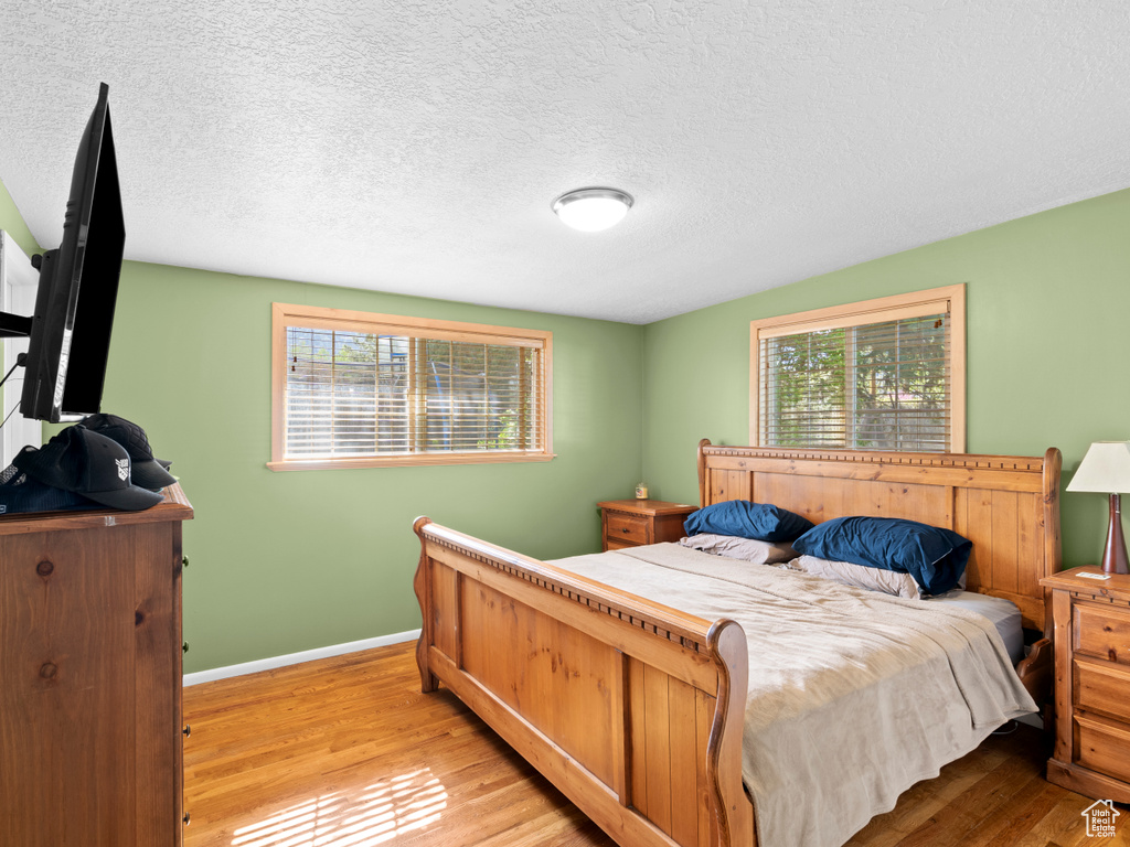 Bedroom with a textured ceiling, hardwood / wood-style flooring, and multiple windows