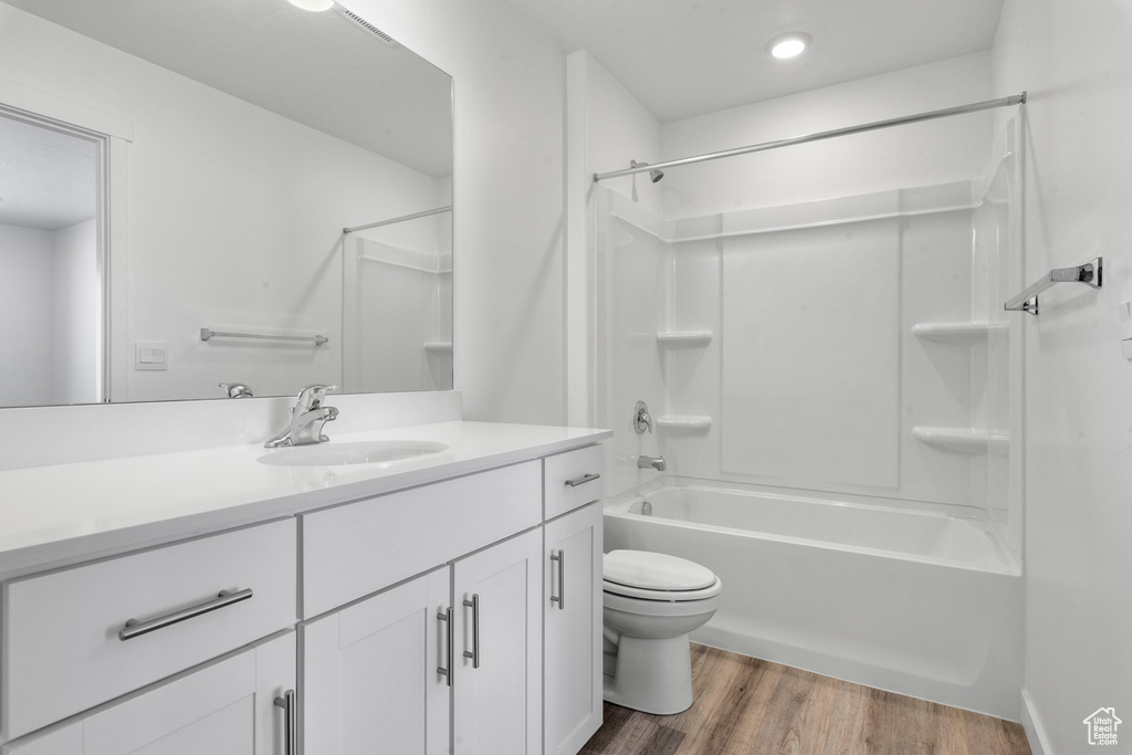 Full bathroom featuring hardwood / wood-style floors, vanity,  shower combination, and toilet