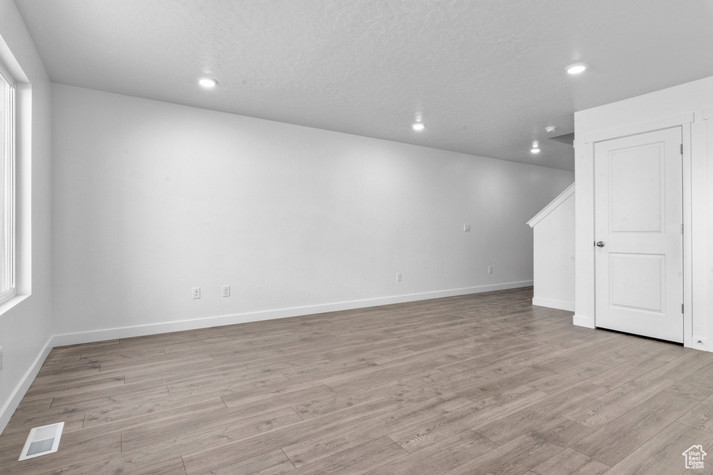 Spare room with a healthy amount of sunlight, light hardwood / wood-style floors, and a textured ceiling