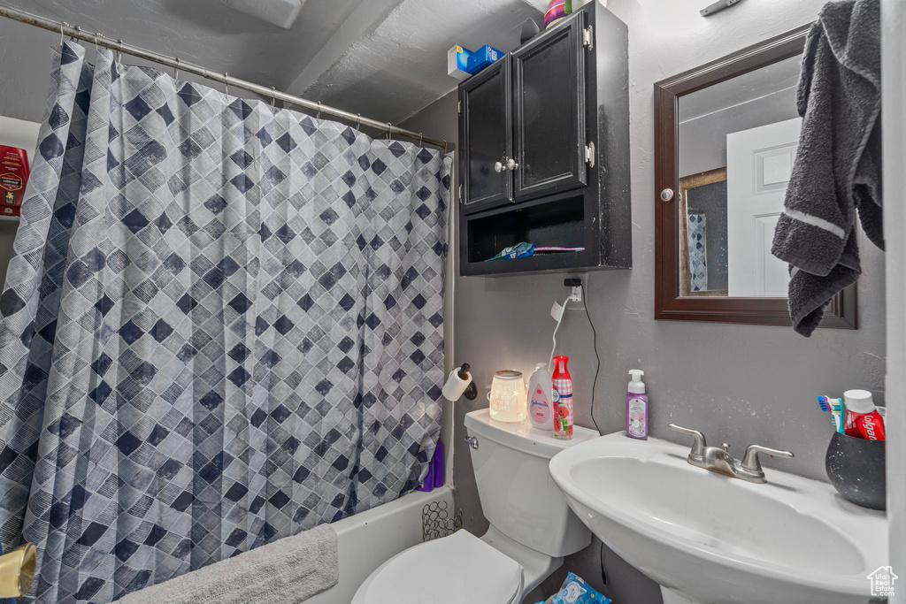 Full bathroom featuring sink, shower / bathtub combination with curtain, and toilet