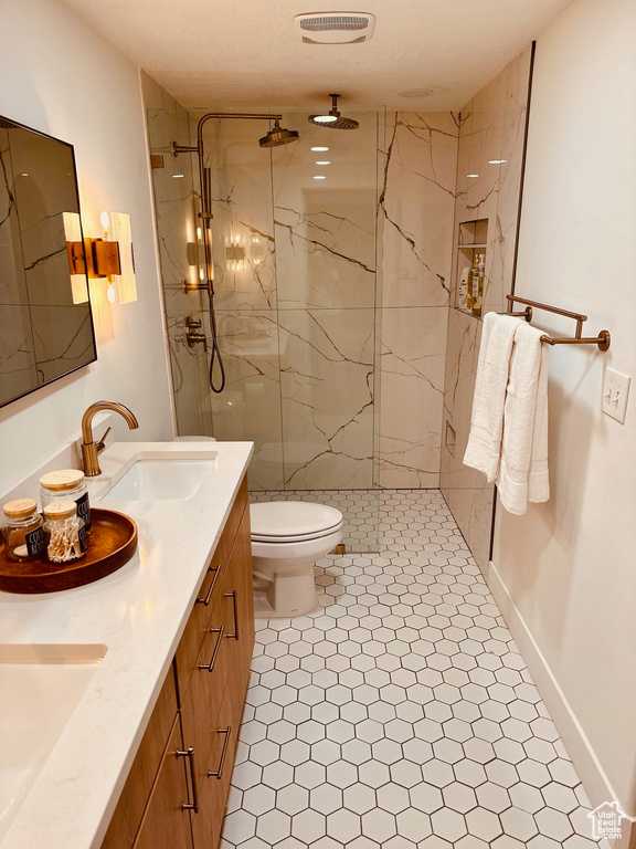 Bathroom featuring double vanity, a shower with door, toilet, and tile flooring