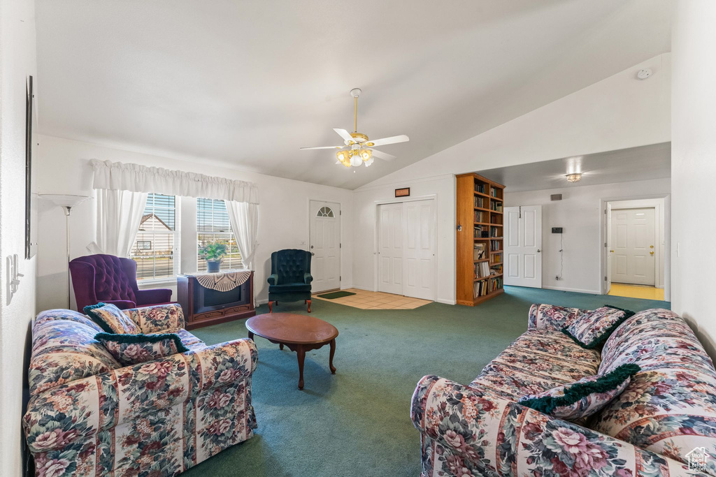 Carpeted living room with ceiling fan and vaulted ceiling