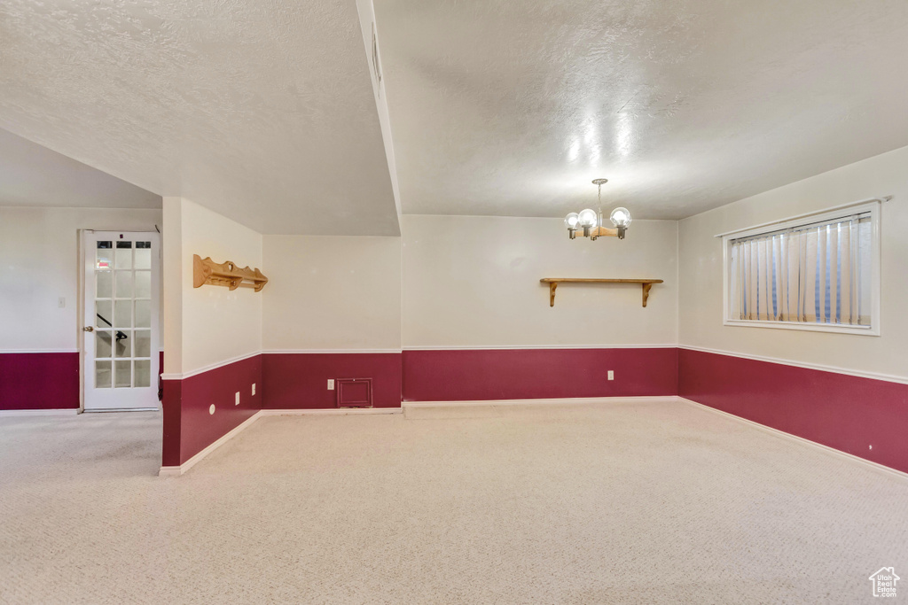 Carpeted empty room with a chandelier and a textured ceiling