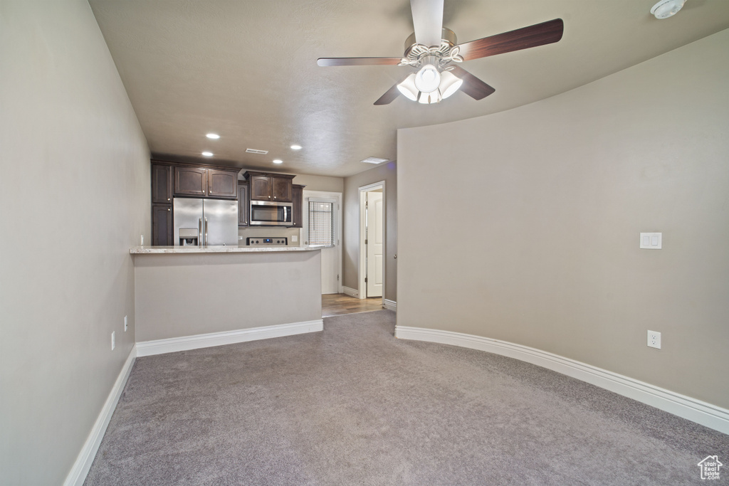 Unfurnished living room with ceiling fan and carpet flooring