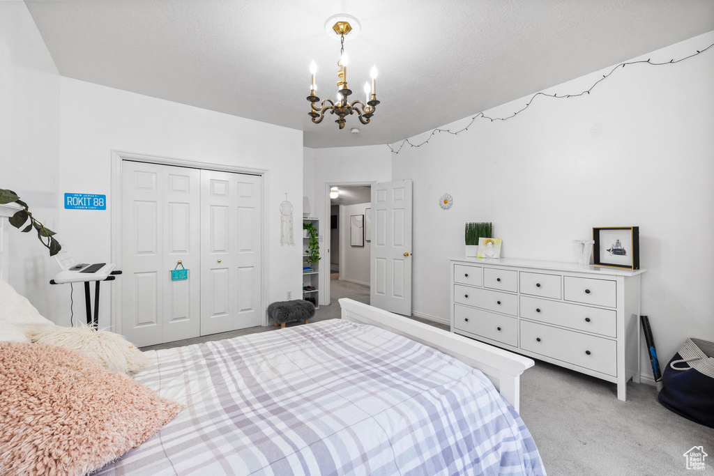 Bedroom featuring light colored carpet, a closet, and a notable chandelier
