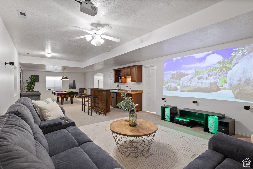 Carpeted living room with ceiling fan, a tray ceiling, and a textured ceiling