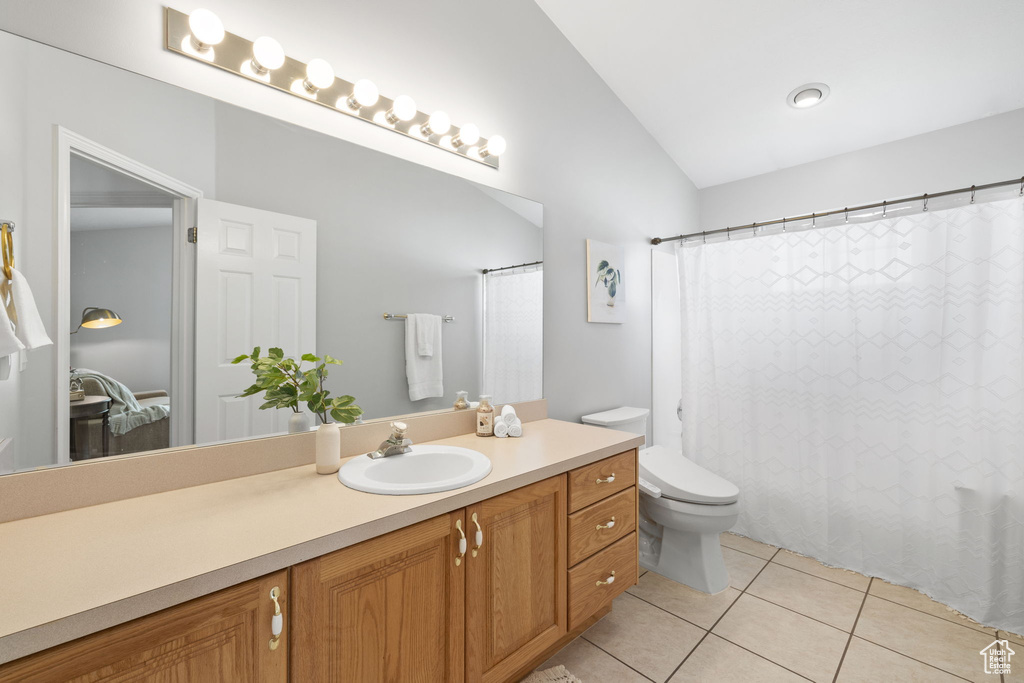 Bathroom with toilet, tile flooring, vanity, and vaulted ceiling