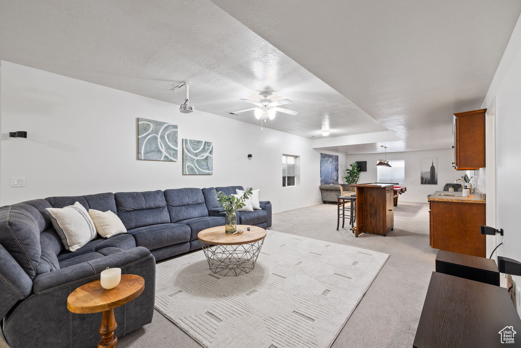 Living room with light colored carpet, ceiling fan, and a textured ceiling