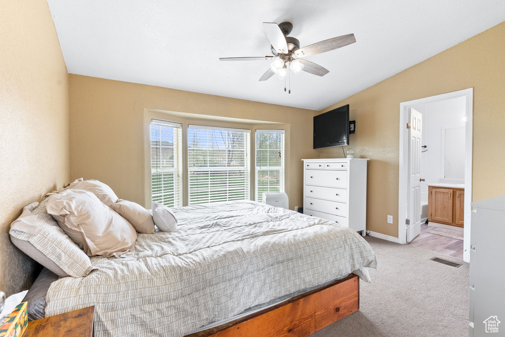 Bedroom featuring light colored carpet, ceiling fan, vaulted ceiling, and connected bathroom