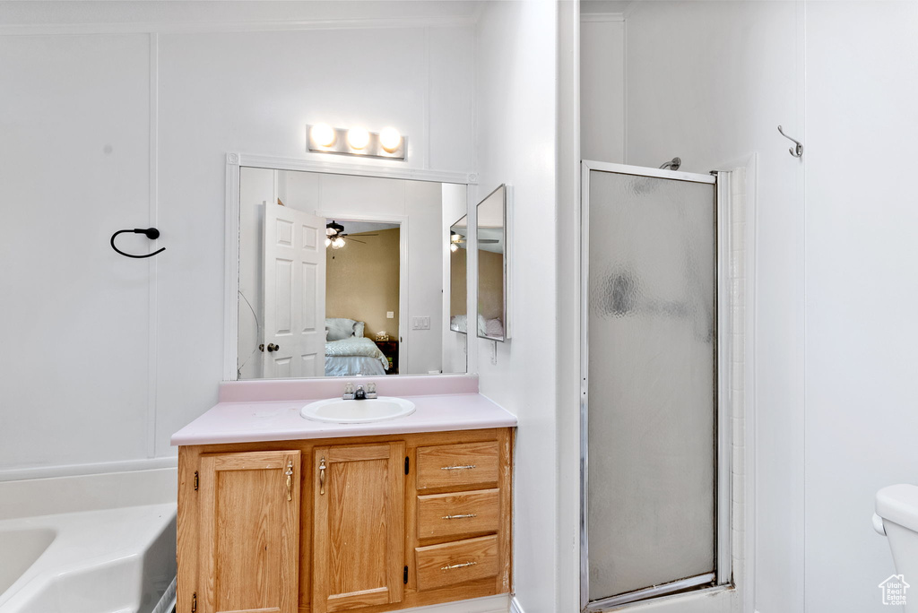 Full bathroom featuring ceiling fan, vanity, toilet, and plus walk in shower
