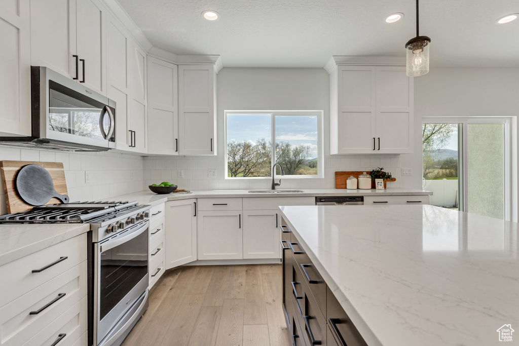Kitchen with backsplash, a wealth of natural light, stainless steel appliances, and white cabinetry