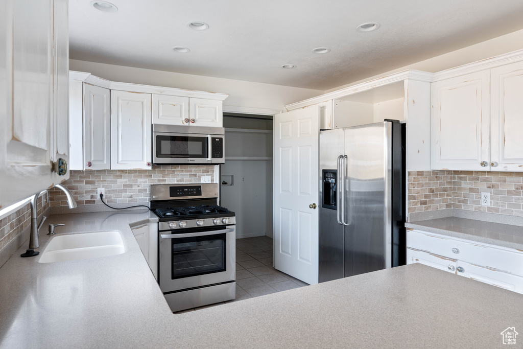 Kitchen featuring white cabinets, sink, appliances with stainless steel finishes, and tasteful backsplash