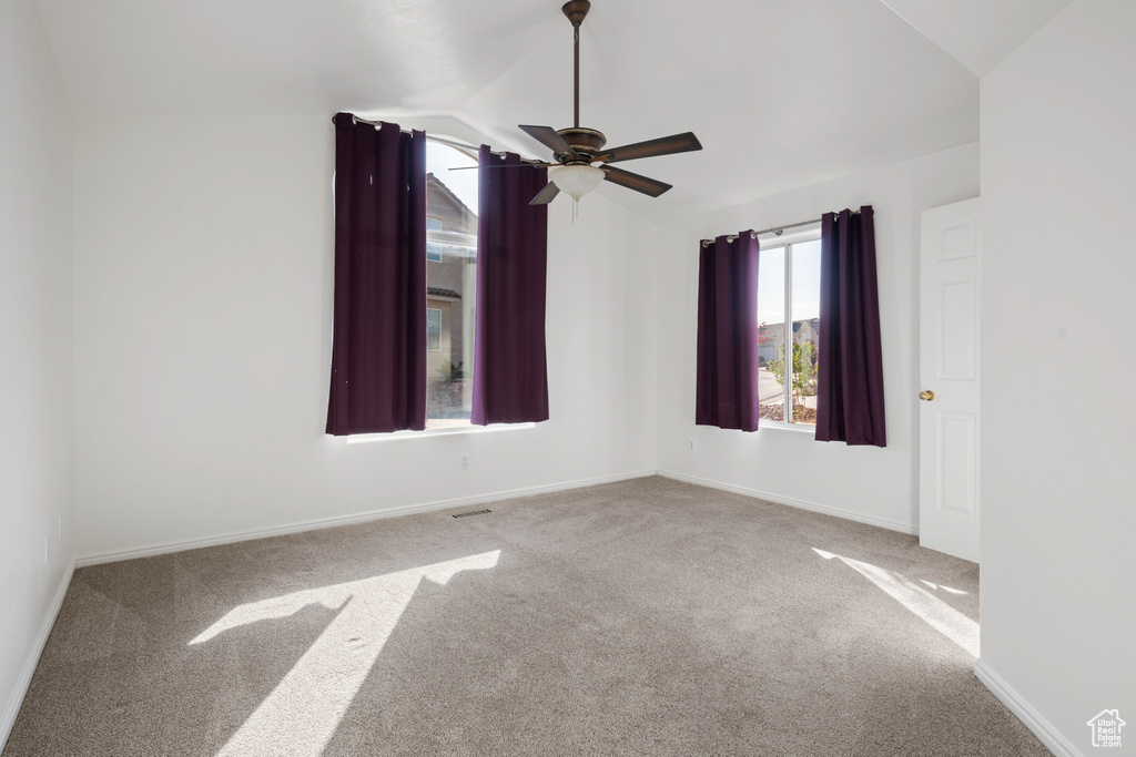 Empty room with vaulted ceiling, ceiling fan, and carpet