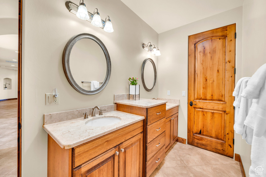 Bathroom featuring vanity with extensive cabinet space, double sink, and tile flooring