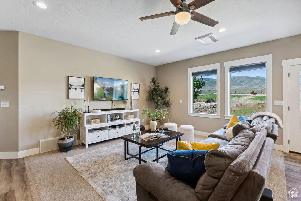 Living room featuring hardwood / wood-style flooring, ceiling fan, a mountain view, and a textured ceiling