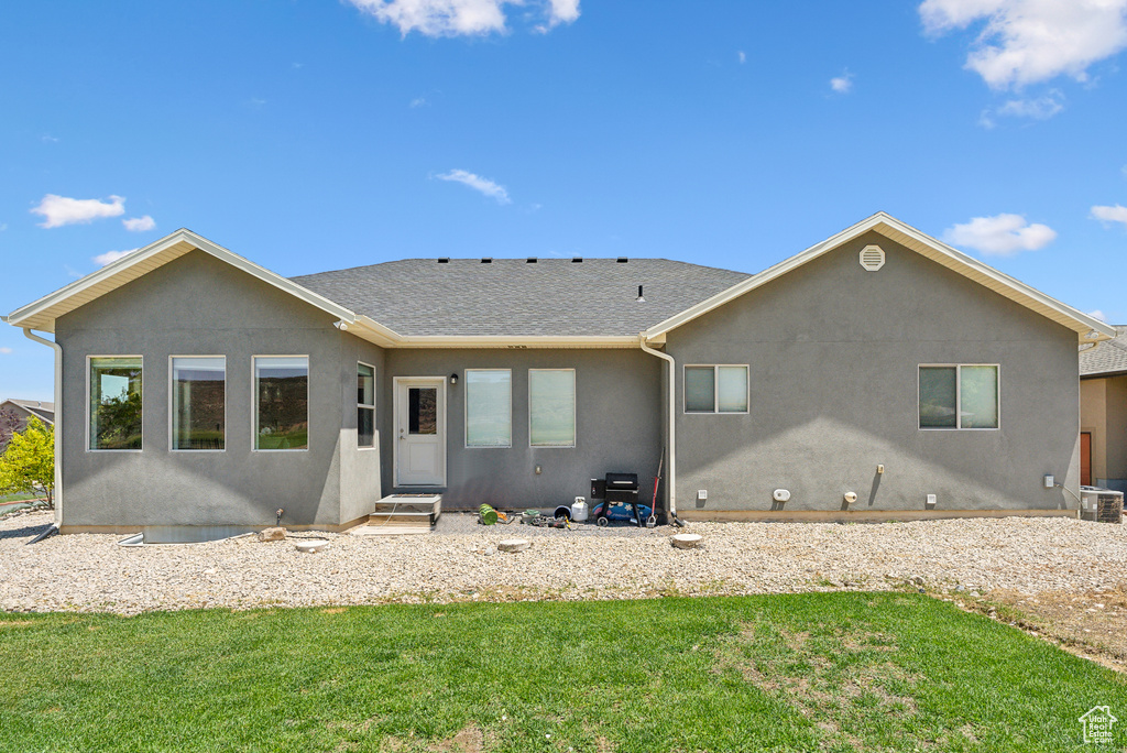 Rear view of house with central AC unit and a yard