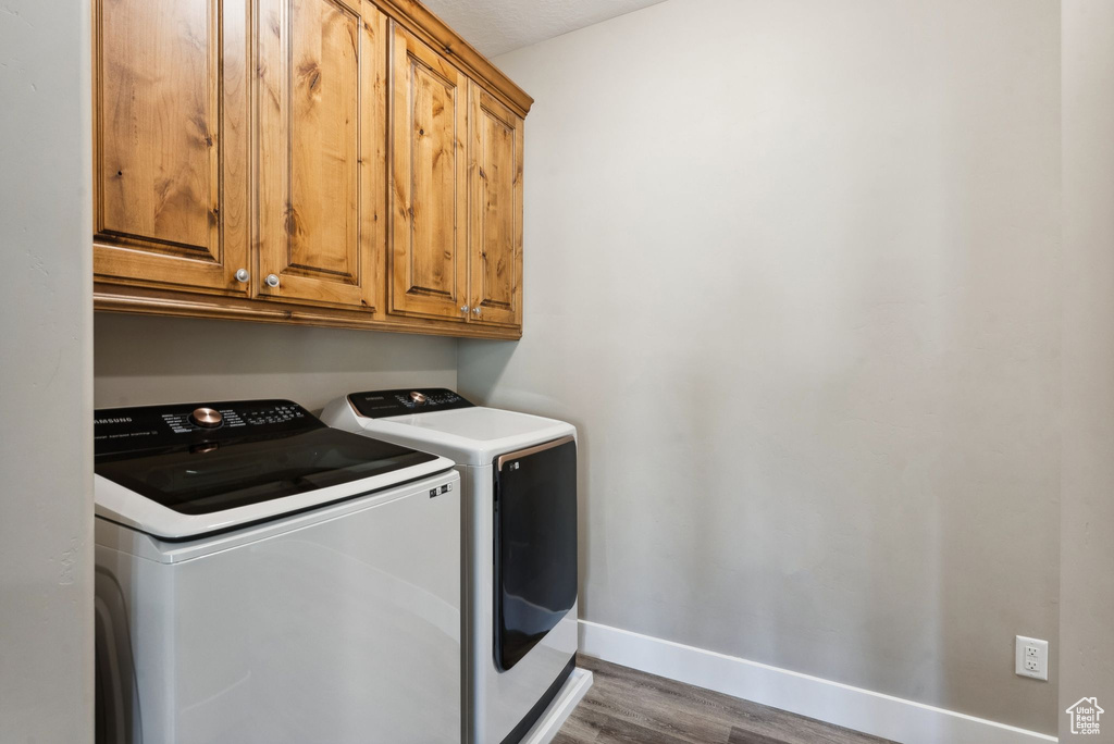 Washroom featuring wood-type flooring, cabinets, and independent washer and dryer