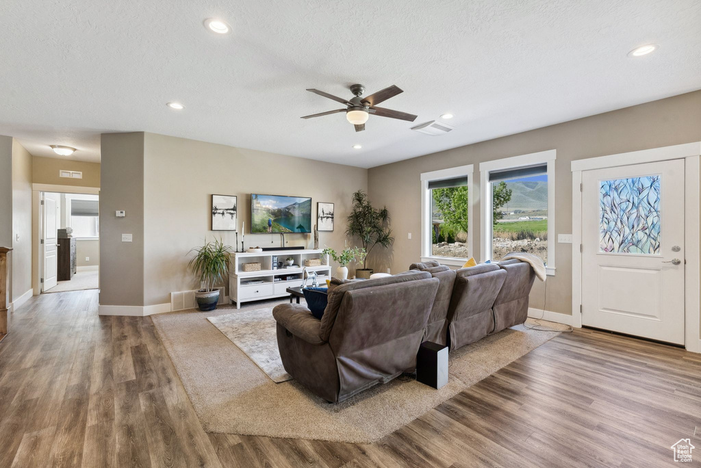 Living room featuring ceiling fan, hardwood / wood-style flooring, and a textured ceiling