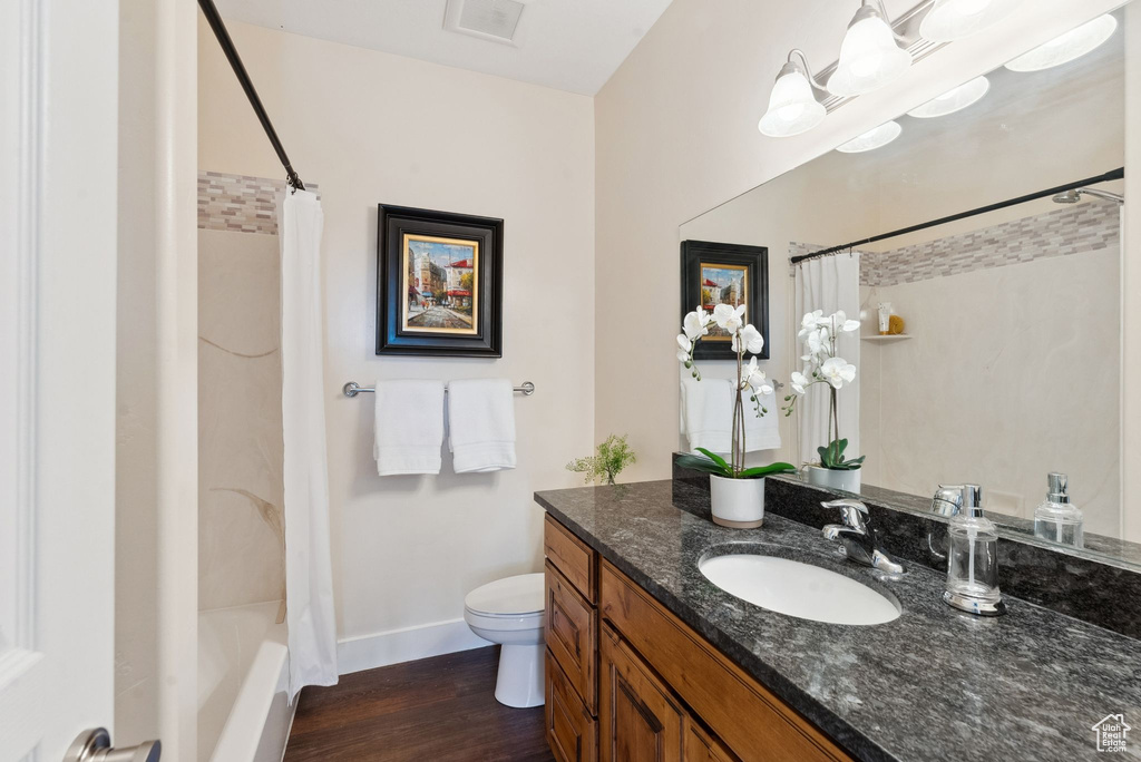 Full bathroom featuring shower / bath combination with curtain, hardwood / wood-style floors, toilet, and vanity