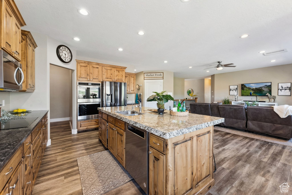 Kitchen featuring appliances with stainless steel finishes, an island with sink, dark hardwood / wood-style floors, sink, and ceiling fan