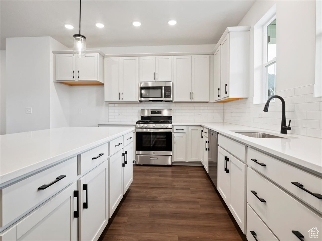 Kitchen featuring backsplash, stainless steel appliances, dark hardwood / wood-style floors, white cabinetry, and sink