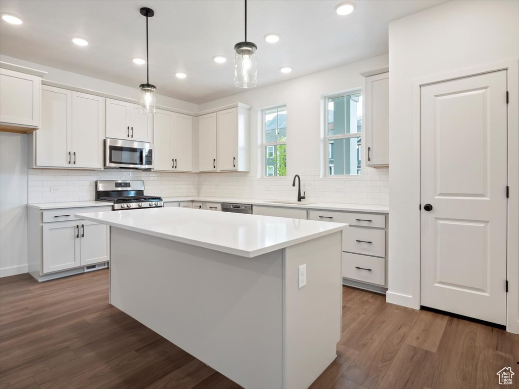 Kitchen featuring dark hardwood / wood-style flooring, white cabinetry, and stainless steel appliances