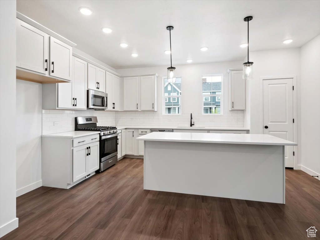 Kitchen featuring a center island, appliances with stainless steel finishes, white cabinets, and dark hardwood / wood-style floors
