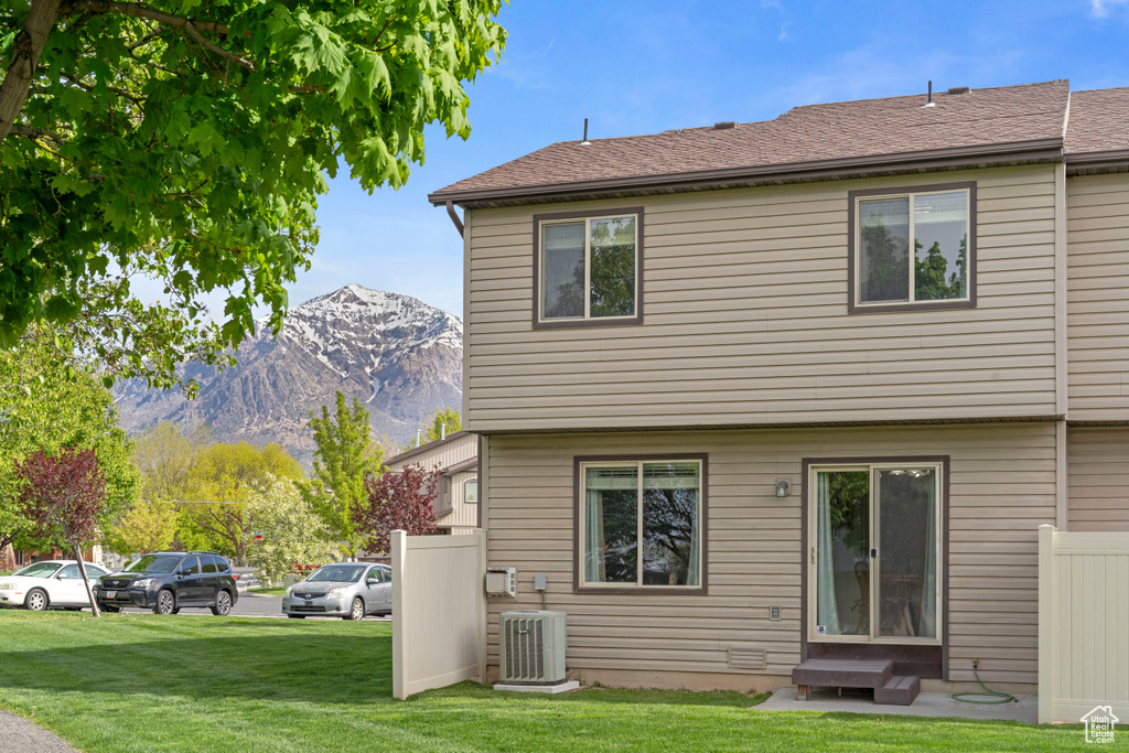 Rear view of property with a mountain view, a yard, and central AC