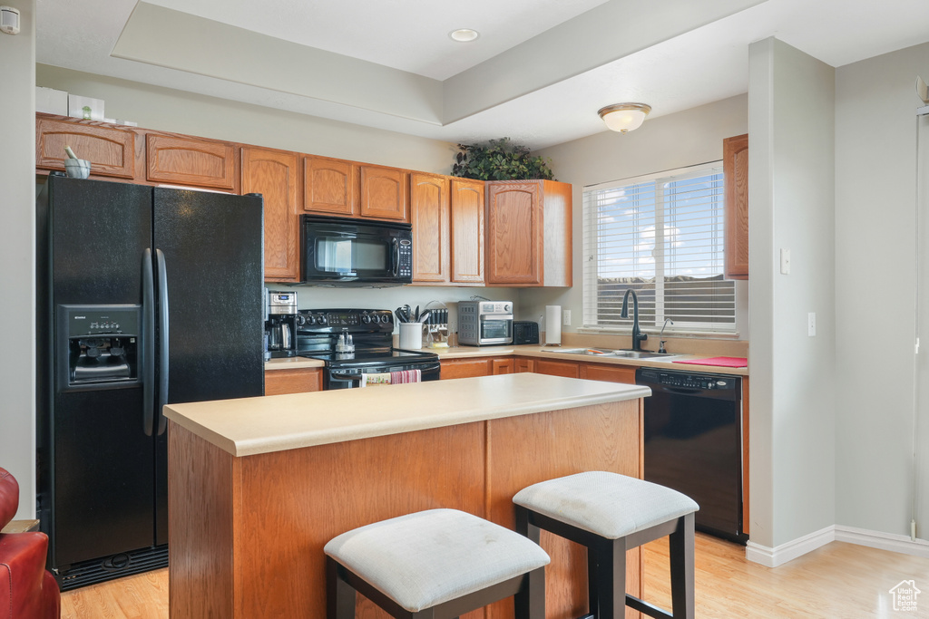 Kitchen featuring a kitchen island, light hardwood / wood-style floors, black appliances, and sink