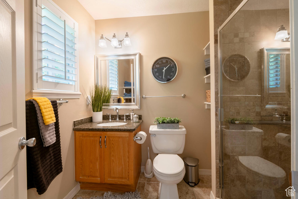 Bathroom featuring large vanity, a shower with shower door, tile floors, and toilet